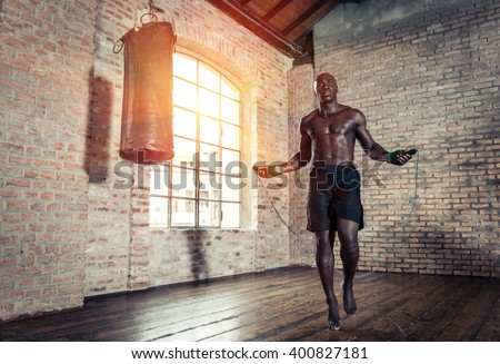 Black fighter training hard in his gym. Man using rope in an old gym,making warm up. concept about sport