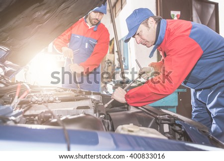 Two mechanics working on a car . close up on mechanic tools