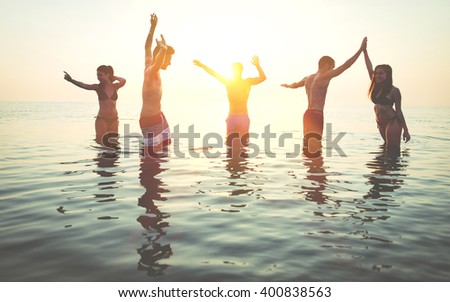 Group of friends making party in the water at sunrise time