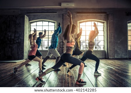 Group of sportive people in a gym training - Multiracial group of athletes stretching before starting a workout session