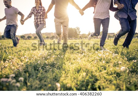 Group of friends running happily together in the grass