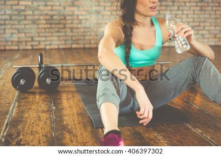 Woman drinking water after training on the sport mat