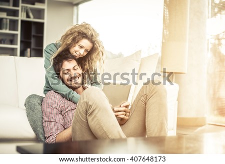 Couple of lovers at home watching the smartphone on the couch - Man and woman relaxing of the sofa, woman leaning head on her boyfriend\'s shoulder
