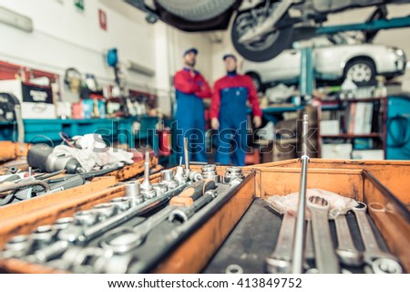 Two mechanics working on a car . close up on mechanic tools
