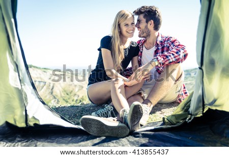 Happy couple having fun on camping. Couple sitting out their tent and sharing happy moments