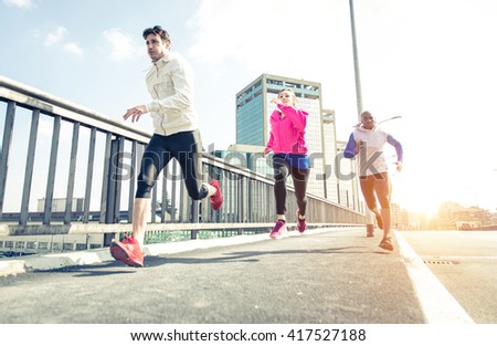 Group of urban runners making sport in an urban area. Three friends running in the morning on the city streets. Floor view, dynamic image