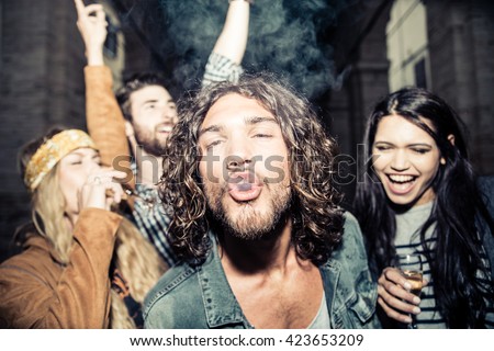 Group of four young friends having party, smoking and drinking alcohol - Best friends clubbing in the night, frontal flash to give realism to the scene