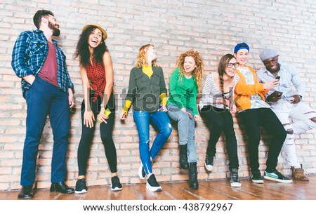 Group of friends having fun together. Mixed race group of teenagers posing against the brick wall