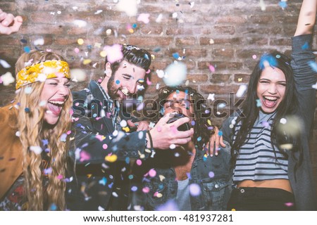 Friends making big party in the night. Four people throwing confetti and drinking champagne