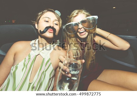 Party girls celebrate in Hollywood drinking champagne on a convertible car