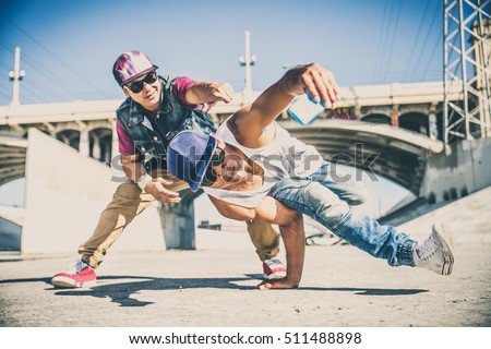 Two bboys doing some stunts - Street artist breakdancer taking an acrobatic selfie outdoors