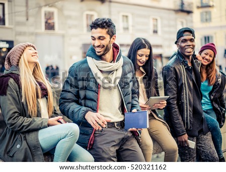 Group of multi-ethnic friends walking on the streets and smiling - Young people having fun outdoors