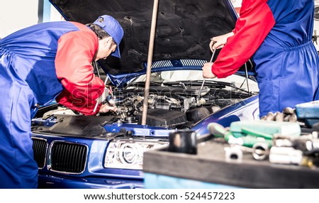 Two mechanics working on a car
