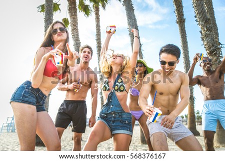 Group of friends having party on the beach, dancing and drinking cocktails