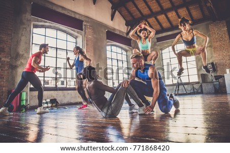 Multi-ethnic group of people training in a gym - Personal  trainer and sportive persons  in a fitness class