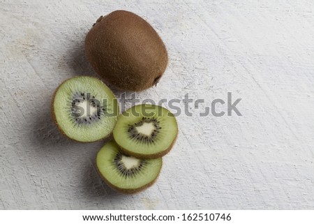 Sliced kiwi fruit, one whole kiwi fruit, on white wooden background