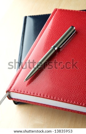 The notebook with the pen lays on a grey background