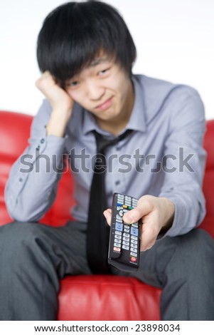 The smiling young man in a grey shirt watches TV