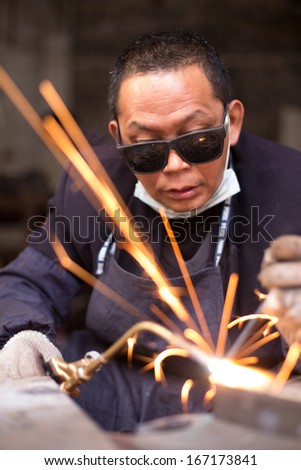 Industrial worker welding metal with sparks portrait orientation