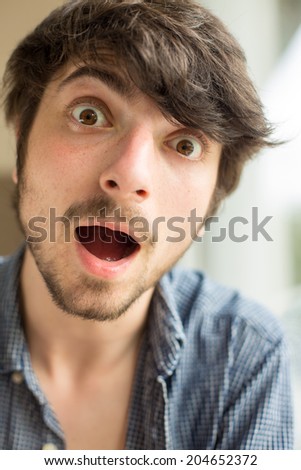 A young male model looks very excited, happy and tries to laugh