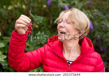 A nice elderly woman is about to eat a red currant (type of berry)