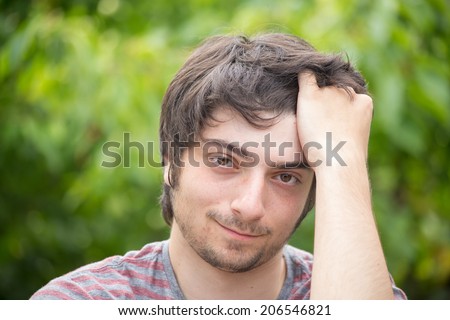 A young male model is brushing through his hair attractively looking into the camera