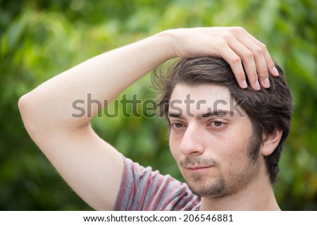 A young male model is brushing through his hair attractively