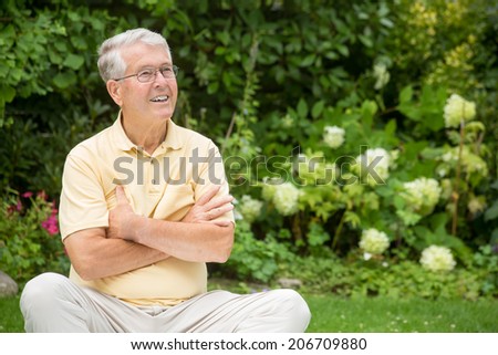 An elderly man is lifting his eyebrows with his arms crossed