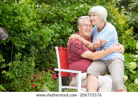 An romantic elderly couple sitting outside. The wife is looking lovingly at her husband