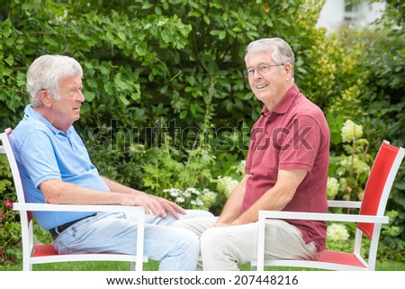 Two elderly men are sitting and enjoying the time together - from the side
