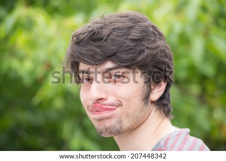A young male model is touching his nose with his tongue