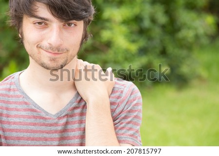 A young male model is smirking attractively into the camera while holding his back