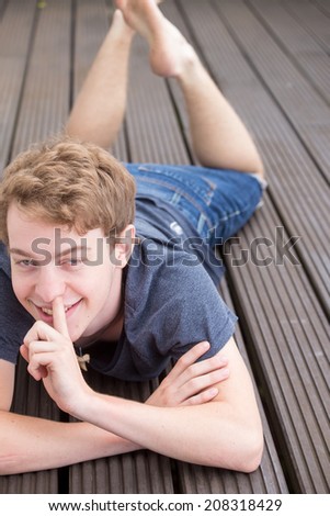 A young blonde male model is picking his nose laughing