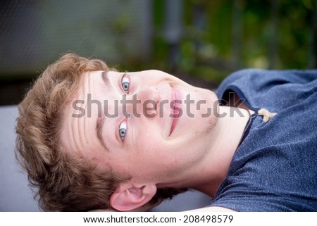 A young blonde male model is lifting his eyebrows in wonder and surprise
