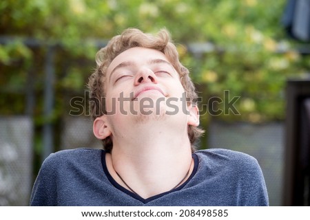A young blonde male model is enjoying the sun and the fresh air
