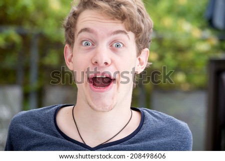 A young blonde male model is very surprised and happy