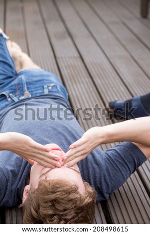 A young blonde male model is lying on his back and is dealing with problems