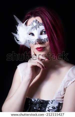 Mysterious red head and blue eyed girl with a white mask on black background.