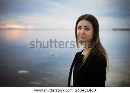 Smiling woman portrait against sea and moody sky.