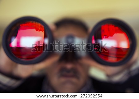 Man watching outside with binoculars.