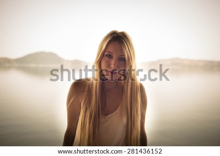 Portrait of a blonde woman foreground the mountains and lake. Bafa lake.