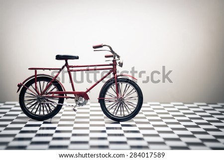 Old Fashion hand made model bcycle on a white background and checked floor.