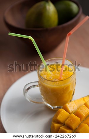 Fresh mango smoothie with ripe mangoes in the wooden bowl