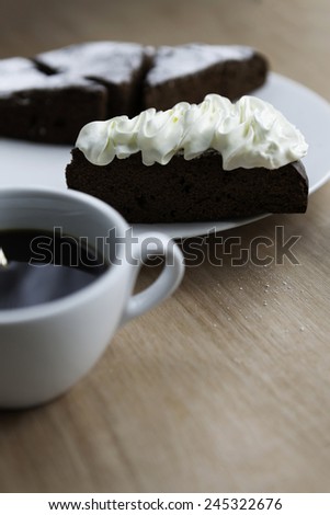 Slice of Belgium chocolate cake with a cup of black coffee closeup