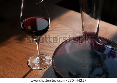 Closeup of the carafe and glass of red wine on the wooden table