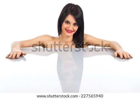 Slim girl smiling on a white background laying on a white desktop