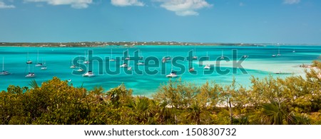 panoramic image of the harbour, or anchorage, in the bahamas near George Town in the Exumas.  Sand bar with small boat dock is off to the right and copy space is available in the clear blue sky