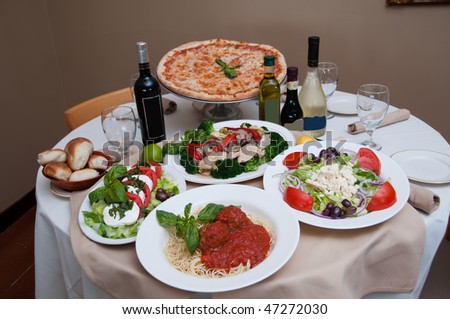 beautiful table of italian salads, pasta, pizza and drinks
