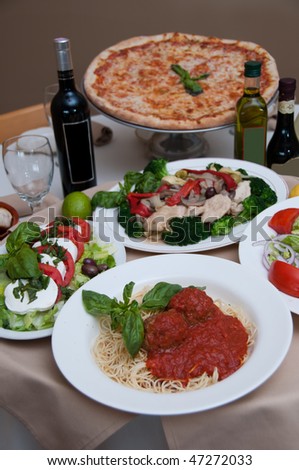 beautiful table of italian salads, pasta, pizza and drinks