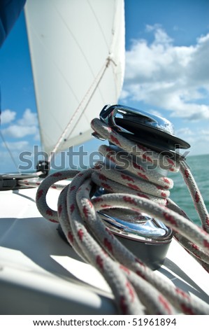 large winch with line wrapped around and set sail in background